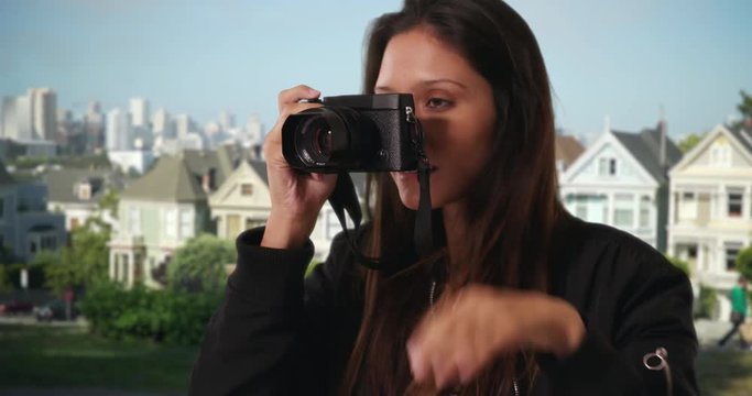 Hipster girl in bomber jacket taking photograph in San Francisco neighborhood with dslr camera, Millennial woman explores the city taking picture near famous painted ladies houses, 4k