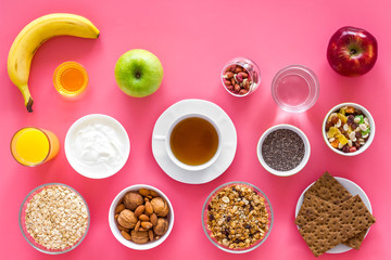 Layout of products for healthy and hearty breakfast. Fruits, oatmeal, yogurt, nuts, crispbreads, chia on pink background top view copy space