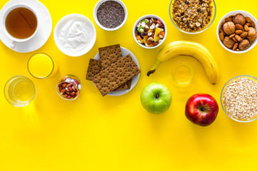 Ideas of healthy hearty breakfast for sportsmen. Fruits, oatmeal, yogurt, nuts, crispbreads, chia on yellow background top view copy space
