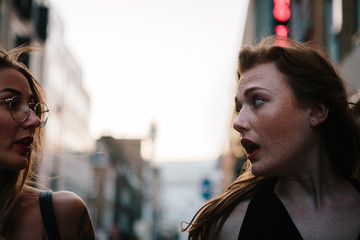 Two attractive millenial women chatting in the street