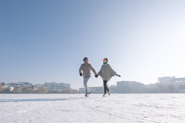 Young couple ice skating on the lake on a bright day