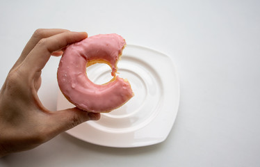 Hand holding bite donut ring with strawberry flavor glaze coating