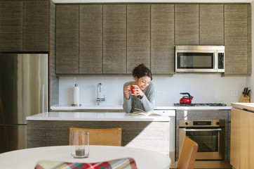Young woman reading in kitchen at home