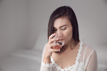 Asian woman in white nightwear drinking water before bedtime for good health at bedroom. Basic...