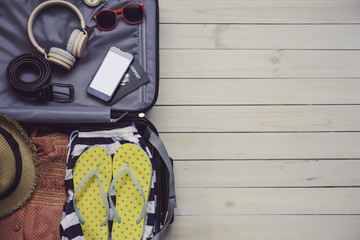 Clothing traveler's Passport, wallet, glasses, smart phone devices, on a wooden floor in the luggage ready to travel.