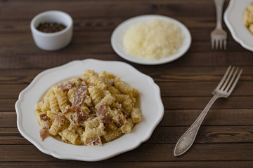 Homemade Pasta carbonara Italian with Bacon, eggs, Parmesan Cheese on white plate on a dark background.