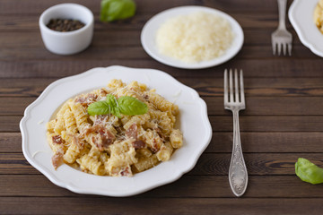 Homemade Pasta carbonara Italian with Bacon, eggs, Parmesan Cheese on white plate on a dark background.