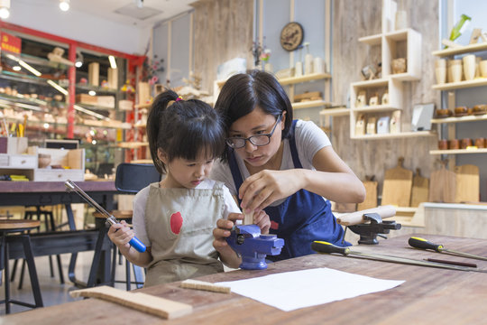 Asian womant with her kid doing carpenter job in the studio