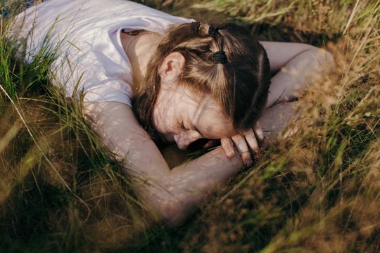Emotional portrait of pre-teen girl laying on the grass and daydreaming