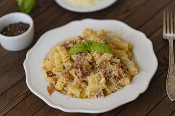 Homemade Pasta carbonara Italian with Bacon, eggs, Parmesan Cheese on white plate on a dark background.