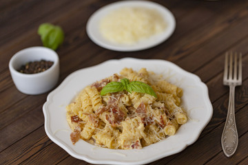 Homemade Pasta carbonara Italian with Bacon, eggs, Parmesan Cheese on white plate on a dark background.