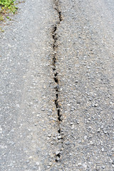 Long deep crack on damaged asphalt road