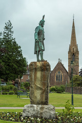 Fort William, Scotland - June 11, 2012: Donald Cameron of Lochiel bronze statue on The Parade with Saint Andrews Church as background under light blue sky.