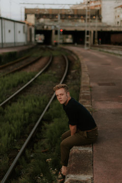 young man sitting in te border of the railway