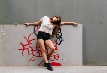 An attractive young woman wearing shorts and T-shirt amongst concrete structures in a city