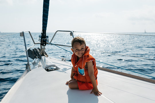 Cute boy in life vest sailing on yacht.