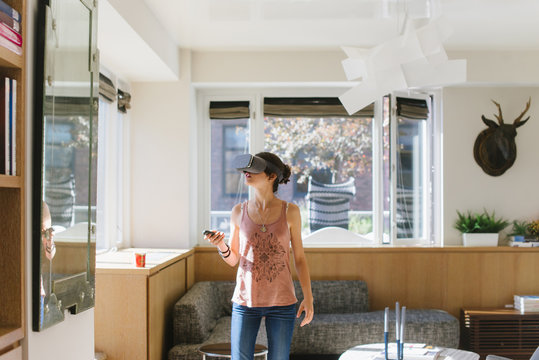 Young woman playing with virtual reality headset at home