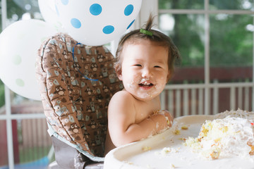 Happy baby eating first birthday cake