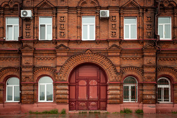 Close-up of a wooden porch with a brown door and old windows with an old house a mansion made of...