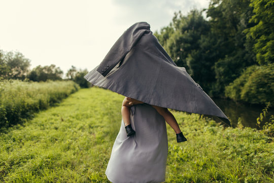 Mother and little daughter hiding under the jacket
