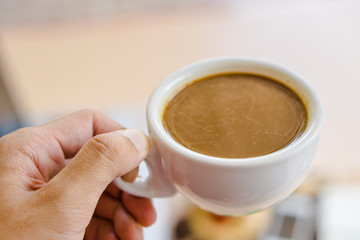 Man put the cup of coffee with his hand.