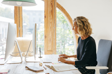 Mature businesswoman working on computer in a modern office.