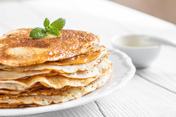 Traditional breakfast pancakes with butter on a plate on a white wooden table close-up