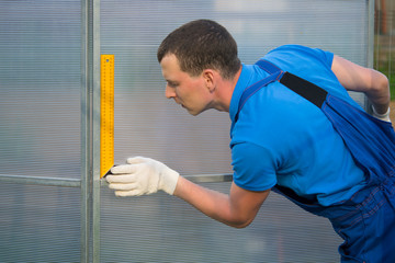 The master checks the correctness of assembling the greenhouse made of polycarbonate