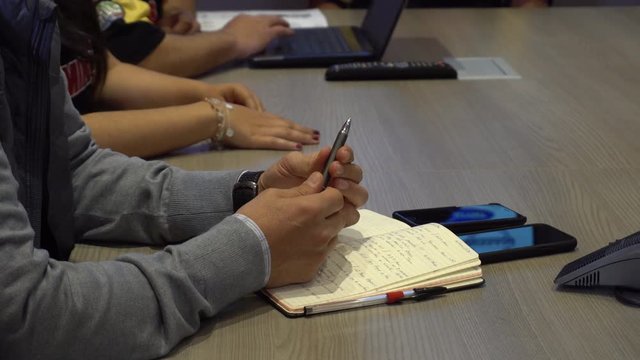 manos de ejecutivo sosteniendo un boligrafo en junta de negocios