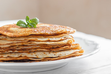 Traditional breakfast pancakes with butter on a plate on a white wooden table close-up