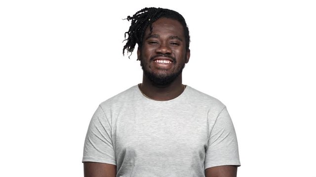 Portrait of handsome african american man in casual t-shirt laughing and expressing joy, isolated over white background. Concept of emotions