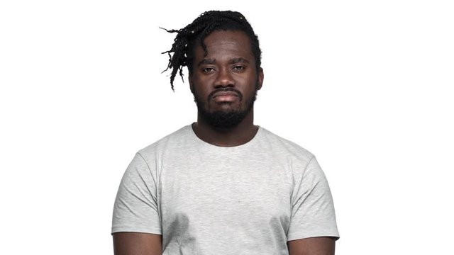 Portrait of big dark skinned guy in casual t-shirt with afro pigtails shaking head in denial or expressing dislike, isolated over white background. Concept of emotions