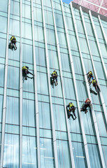 Window washers cleaning the glass facade of a skyscraper, high risk work.