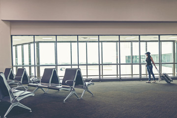 Fototapeta premium Traveler woman plan and backpack see the airplane at the airport glass window, girl tourist hold bag and waiting near luggage in hall airplane departure. Travel Concept .