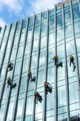 Window washers cleaning the glass facade of a skyscraper, high risk work.