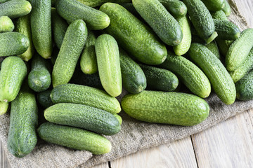 Fresh cucumber, burlap and wooden background