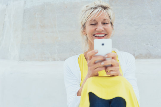 Middle-aged laughing woman using mobile phone