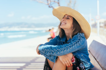 Happy vivacious young woman in a straw sunhat