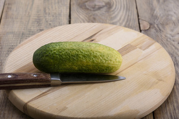 Fresh cucumber and a knife on a cutting board