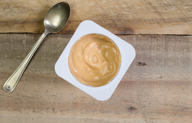 Yogurt in plastic cup on rustic wooden table - Top view photo