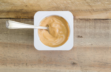 Yogurt in plastic cup on rustic wooden background - Creamy fudge caramel natural yoghurt