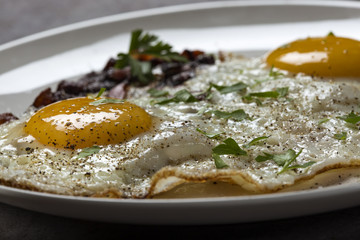 Bacon and eggs with ground pepper and parsley leaves