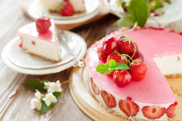 Slice of cheesecake with strawberry filling decorated with cherry jelly and fresh berries. Healthy organic summer dessert pie