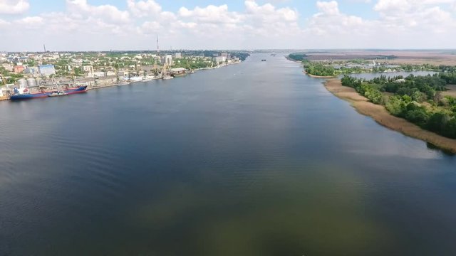 An exciting bird`s eye view of the Dnipro with a huge barge, the picturesque banks covered with greenery, many buildings on a sunny day