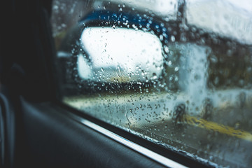 Raindrops on the car rearview mirror. Heavy rain outside