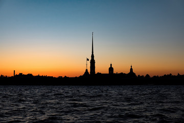 Naklejka premium Peter and Paul fortress with the Palace promenade, Petropavlovskaya krepost, white nights in Saint Petersburg Russia, blue cloudy sky, dark water of the Neva river
