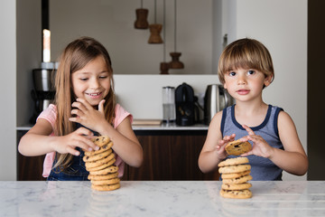 Kids piling up cookies at kitchen counter