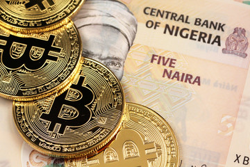 A close up image of Nigerian 5 Naira bank notes with gold bitcoins