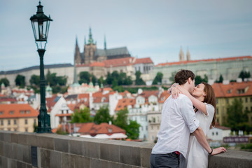 Naklejka premium Young couple kissing in Prague on Charles bridge in Prague
