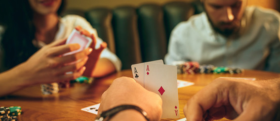 Side view photo of friends sitting at wooden table. Friends having fun while playing board game.